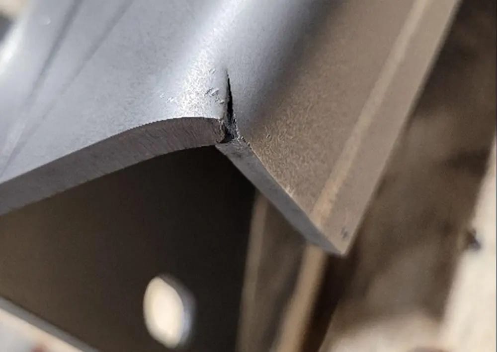 Pictures FIGURE 1. Cracking on the outside radius of the bend, near a cut edge, may be caused by variations in hardness resulting from the heat-affected zone (HAZ) of the cut. Material property variations could also contribute to the issue.