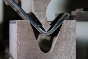 FIGURE 8 In air bending, the die opening establishes the radius and the punch's depth of penetration into the die space establishes the bend angle. This further demonstrates how crucial it is to keep the flange length at a minimum. This bend might not fit firmly on the die if it were nearer the plate edge.